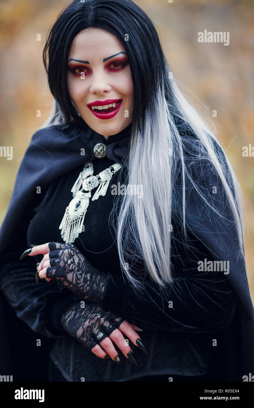 Fotos von lächelnden Vampir Mädchen mit den schwarzen Umhang mit Amulett  gegen den Hintergrund der Herbst Wald Stockfotografie - Alamy