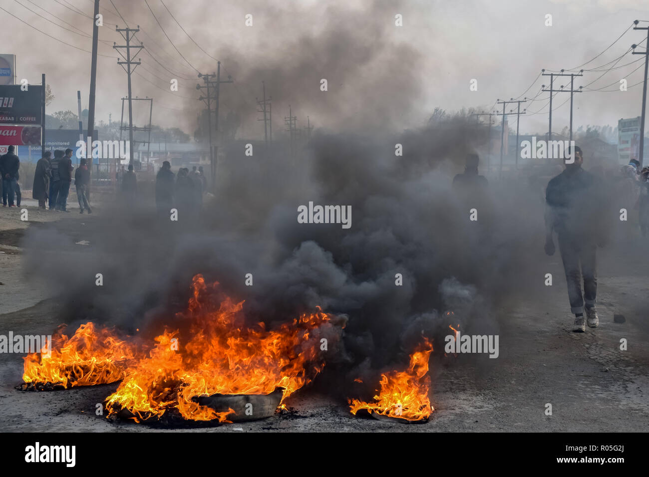 Ein Kaschmirischen Mann gesehen auf dem Weg zum brennenden Reifen während der Auseinandersetzungen. Beamte sagen, daß zwei Rebellen in einem Schusswechsel mit der indischen Regierung Truppen getötet wurden, Auseinandersetzungen ausgebrochen im Bereich der Pampore Pulwama einige 20 km ab Sommer Hauptstadt Srinagar, nachdem die Nachricht verbreitete sich in der ganzen Gegend. Stockfoto