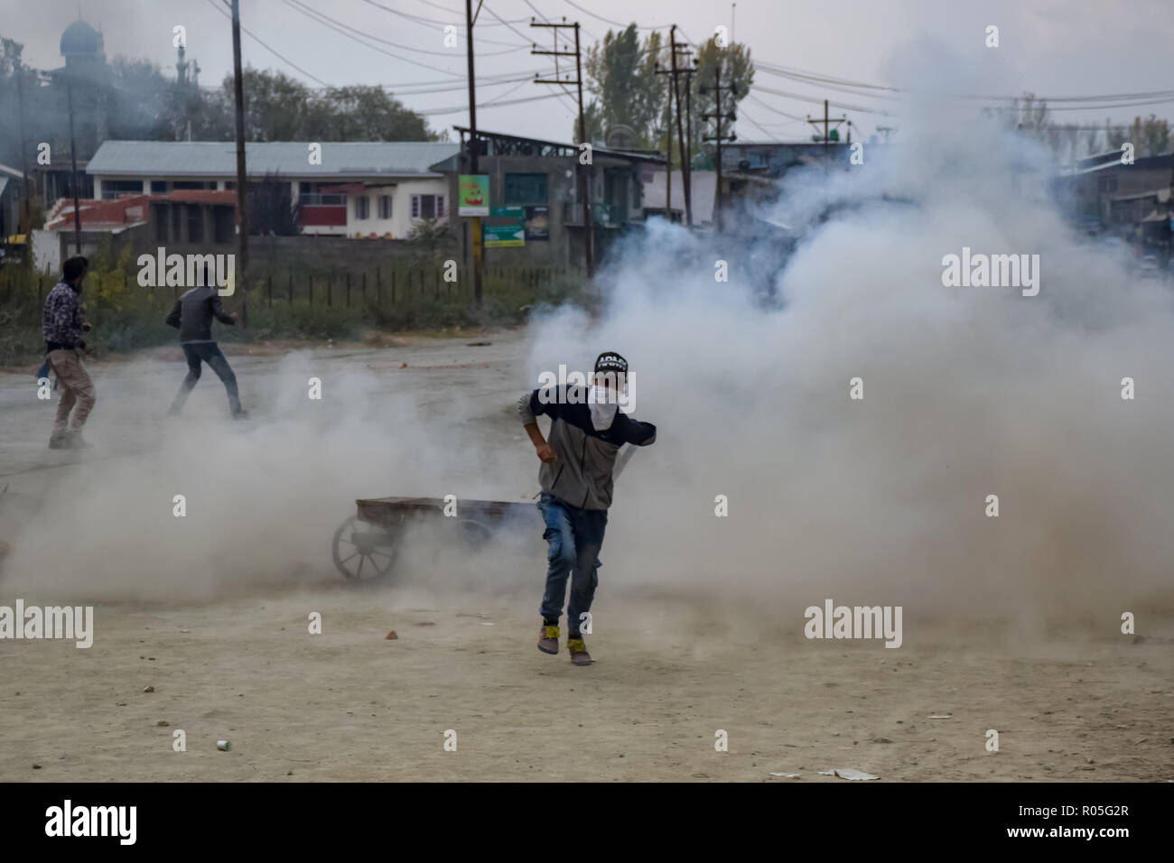Ein Demonstrant in Kaschmir gesehen laufen für Deckel als indische Kräfte Lob-gas Rauch Kanister neben ihm bei den Auseinandersetzungen. Beamte sagen, daß zwei Rebellen in einem Schusswechsel mit der indischen Regierung Truppen getötet wurden, Auseinandersetzungen ausgebrochen im Bereich der Pampore Pulwama einige 20 km ab Sommer Hauptstadt Srinagar, nachdem die Nachricht verbreitete sich in der ganzen Gegend. Stockfoto