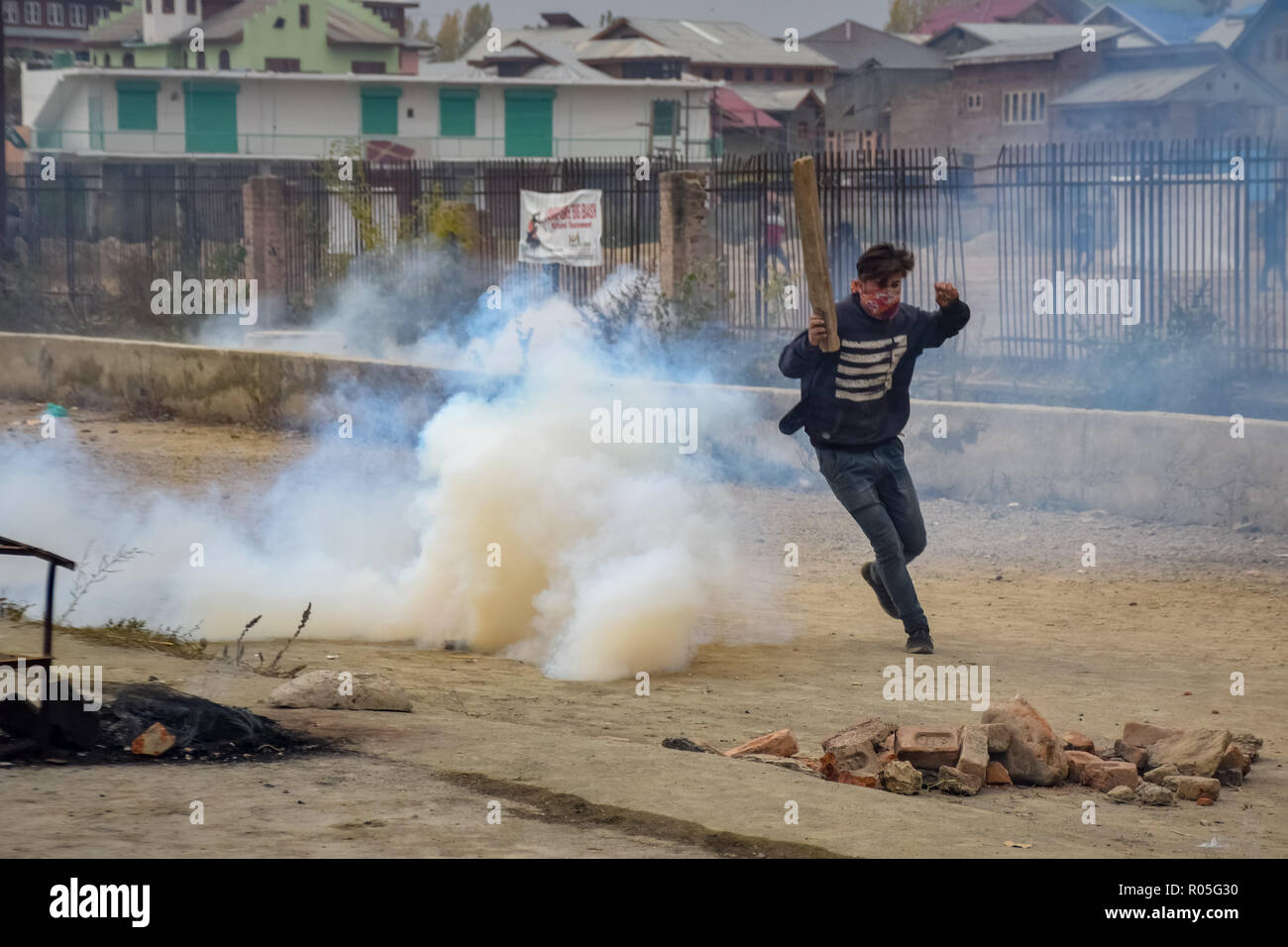 Ein Demonstrant in Kaschmir gesehen laufen für Deckel als indische Kräfte Lob-gas Rauch Kanister neben ihm bei den Auseinandersetzungen. Beamte sagen, daß zwei Rebellen in einem Schusswechsel mit der indischen Regierung Truppen getötet wurden, Auseinandersetzungen ausgebrochen im Bereich der Pampore Pulwama einige 20 km ab Sommer Hauptstadt Srinagar, nachdem die Nachricht verbreitete sich in der ganzen Gegend. Stockfoto