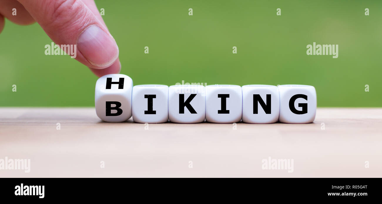 Hand dreht einen Würfel und Änderungen das Wort 'Wandern' zu 'Radfahren' Stockfoto