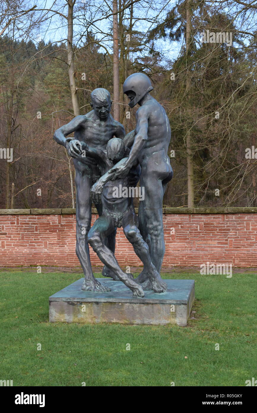 Eine Bronzestatue unter blauem Himmel im Winter in einem Krieg Friedhof zeigt zwei Männer, die ein tödlich verletzte Opfer als ein Symbol der Hilflosigkeit. Stockfoto