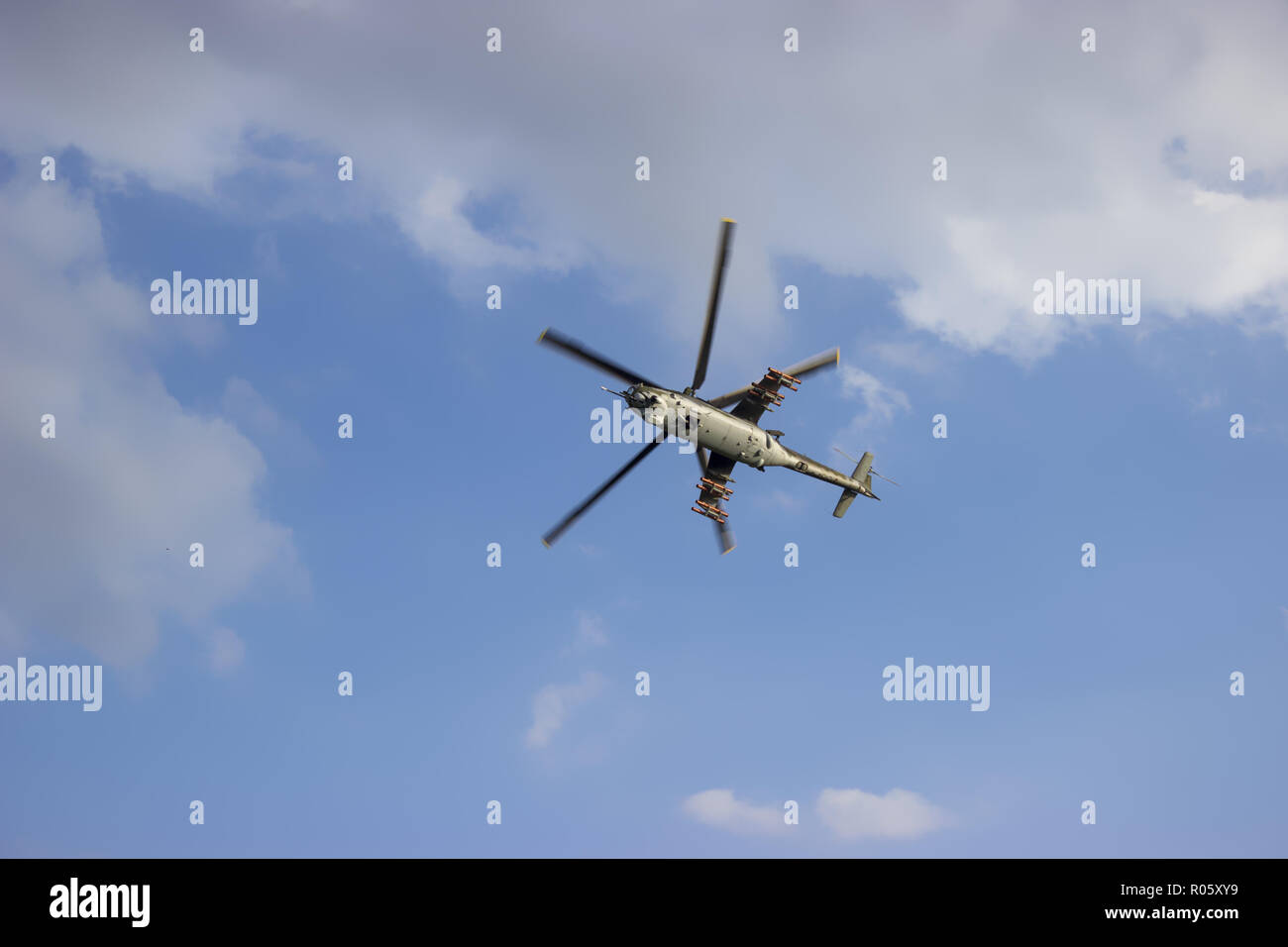 Kampfhubschrauber auf blauer Himmel mit weißen Wolken. Ansicht von unten. Stockfoto