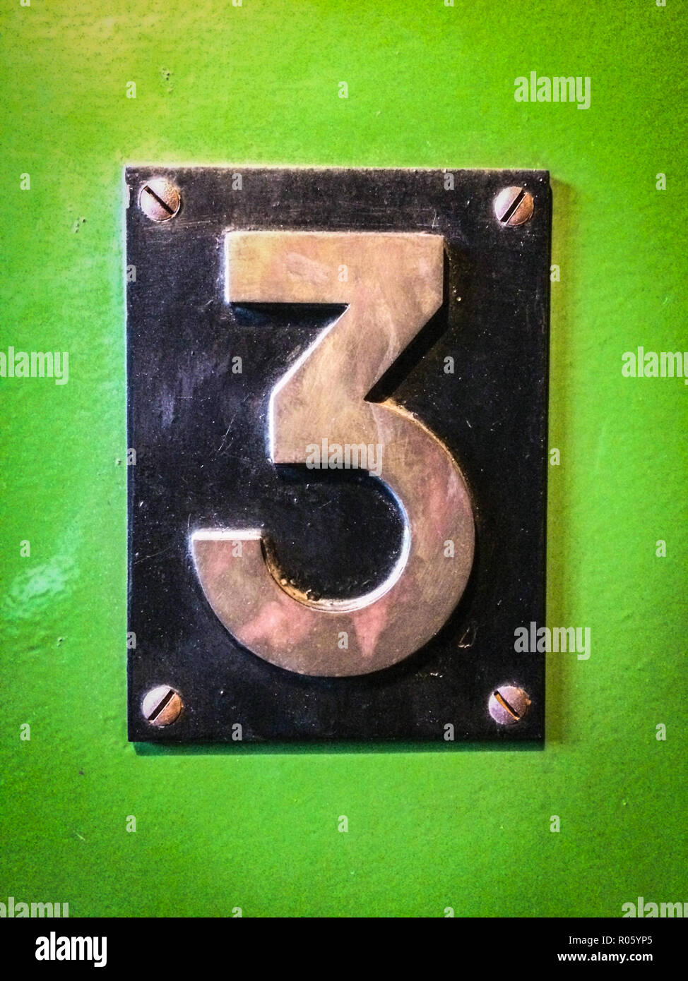 Nummer 3, Nummer drei Metall Schild auf grünem Hintergrund Stockfoto