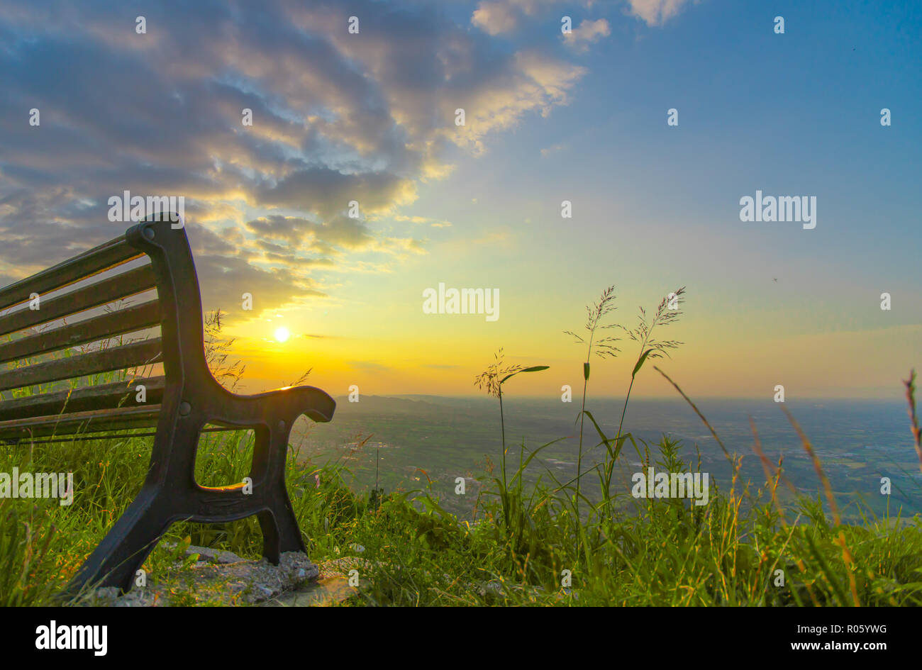 Eine Bank vor der wunderschönen Sonnenaufgang auf den Hügeln begrünt Stockfoto