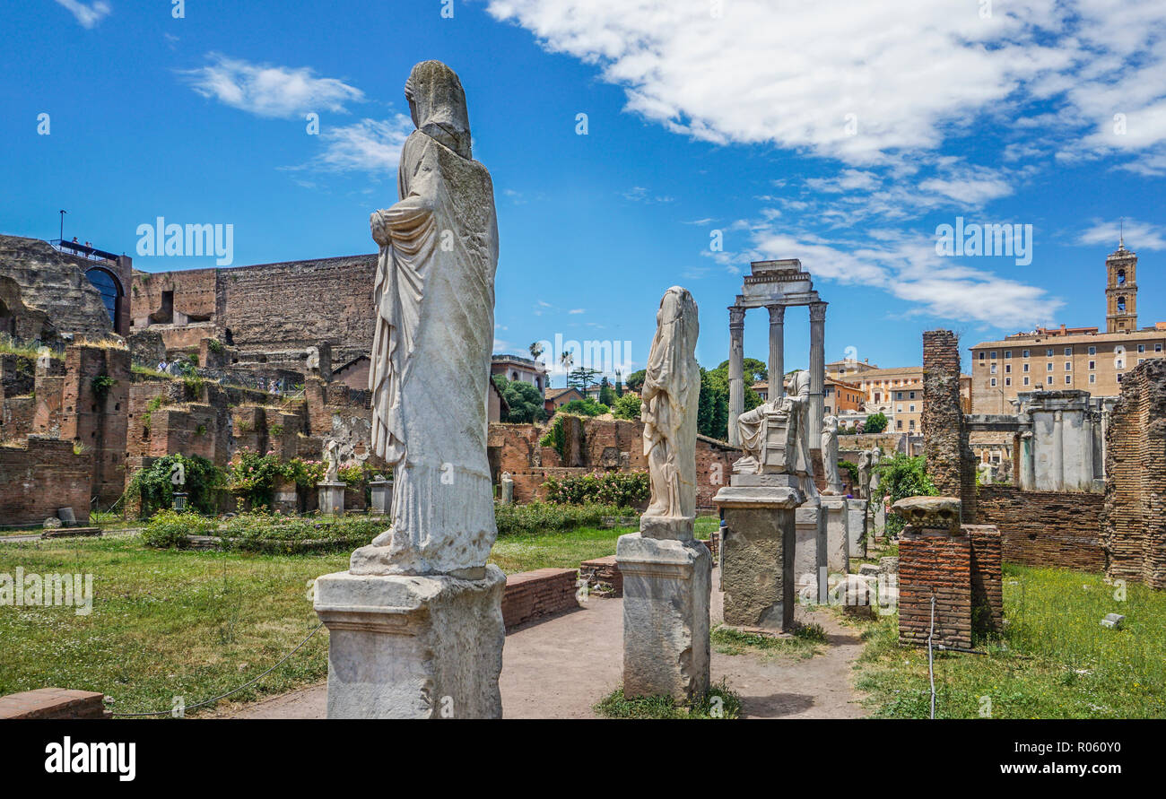 Römische Statuen auf der Website des Hauses der Vestals im Forum Romanum mit den drei verbleibenden korinthischen Säulen der Tempel von Castor und Pollux in Stockfoto