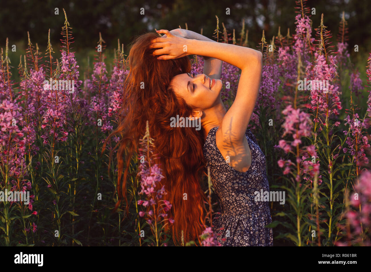 Schöne lächelnde Mädchen in Feld, sun Hintergrundbeleuchtung, Sunrise, Orange Farben Stockfoto