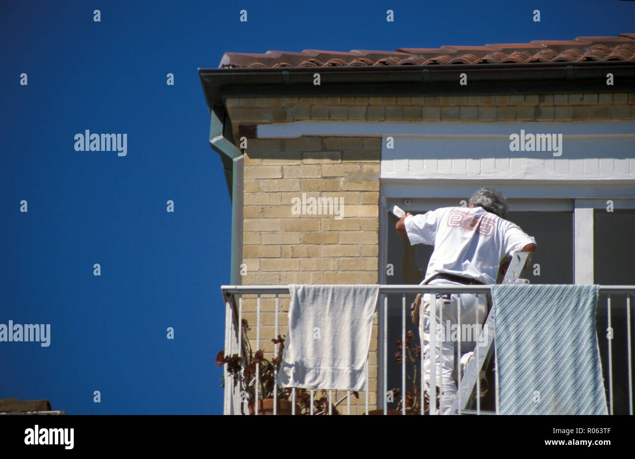 Hausmaler bei der Arbeit, der die Fensterrahmen eines vorstädtischen Backsteinhauses in Sydney, New South Wales, Australien, malte Stockfoto