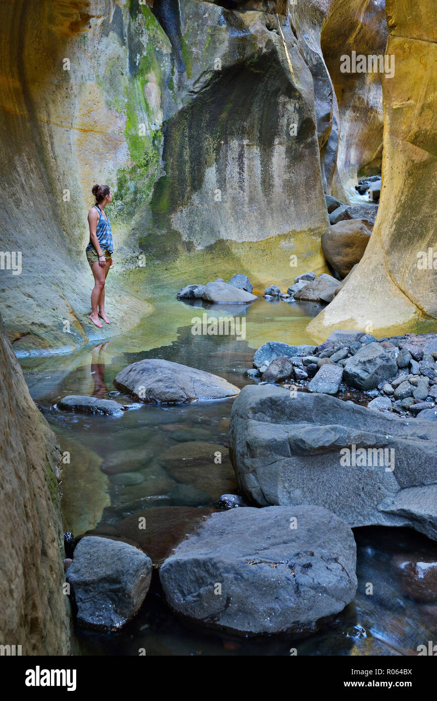 Nach kaukasischen Frauen stehen durch den Stream im Tunnel. National Park Ukhahlamba Drakensberg, Kwazulu Natal Provinz, Südafrika Stockfoto