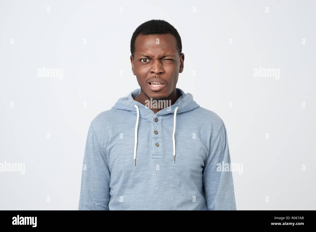 Junge afrikanische Mann im blauen Hemd mit verwirrten Ausdruck auf weißem Hintergrund. Stockfoto