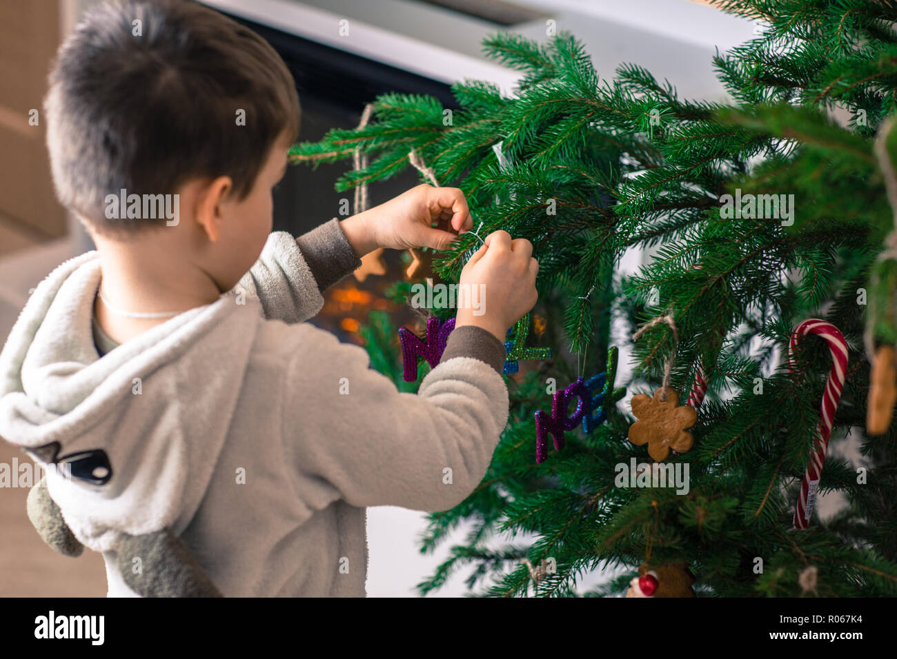 Süßes kleines Kind ist schmücken den Weihnachtsbaum im Innenbereich. Frohe Weihnachten und schöne Feiertage Konzept Stockfoto