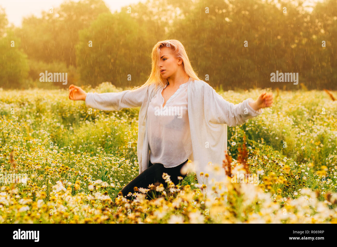 Porträt der jungen Mädchen tanzen in Kamille Feld unter dem Regen Stockfoto