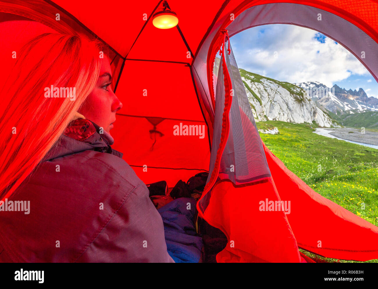 Junge Mädchen schaut aus einem roten Zelt, unteren Segnesboden, Flims, Bezirk Imboden des Kantons Graubünden (Graubünden), Schweiz, Europa Stockfoto