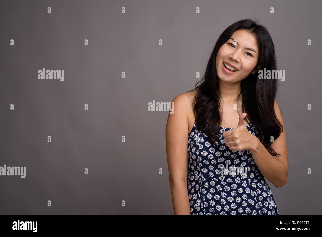 Asiatische Frau trägt blaue Kleid gegen grauer Hintergrund Stockfoto