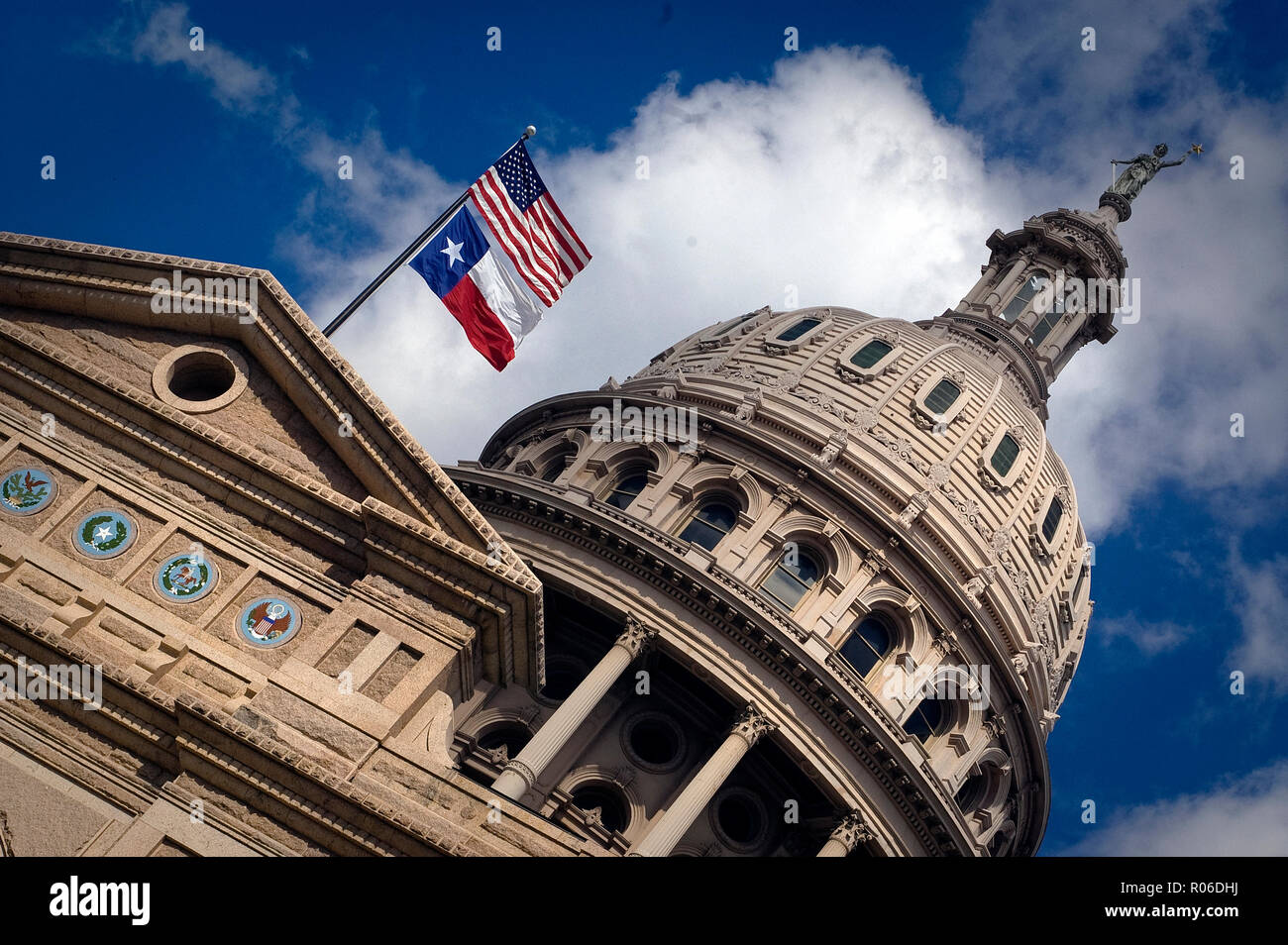 Amerikanische und Texas Flaggen über die Texas Capitol Gebäude in Austin, Texas, USA, fliegen. Über dem Eingang sind Symbole (Dichtungen) für Six Flags, die über das staatliche geflogen sind (Spanien, Mexiko, Frankreich, Republik Texas, die Konföderierten Staaten, und die Vereinigten Staaten. Stockfoto