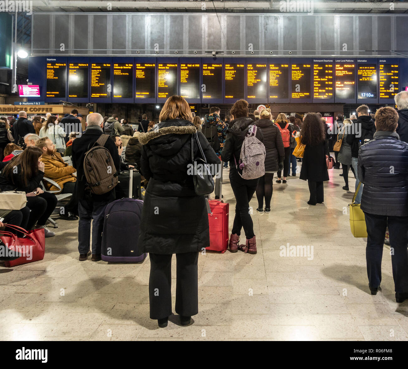 Passagiere, Männer und Frauen, Warten auf die Züge und auf der Anzeigetafel in der bahnhofshalle Hauptbahnhof von Glasgow, Schottland, Großbritannien Stockfoto