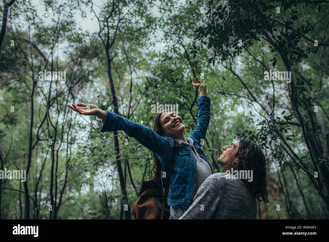 Junge Frau, die Arme, während sie von ihrem Freund durchgeführt. Dating Paare genießen den Regen im Wald. Stockfoto