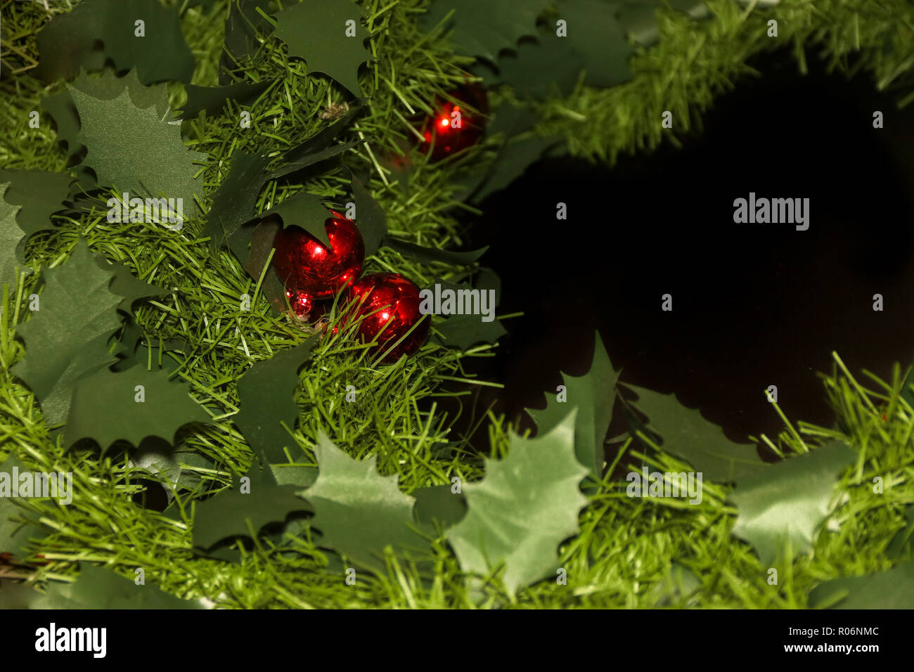 Neues Jahr künstlicher Kranz mit roten Kugeln auf schwarzem Hintergrund Stockfoto