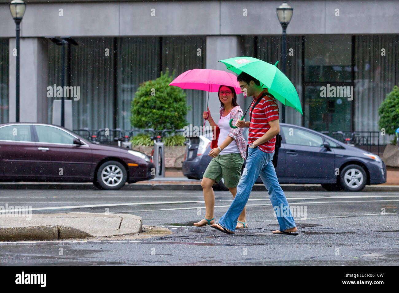Ein Paar, das an einem regnerischen Tag mit Regenschirmen läuft - USA Stockfoto