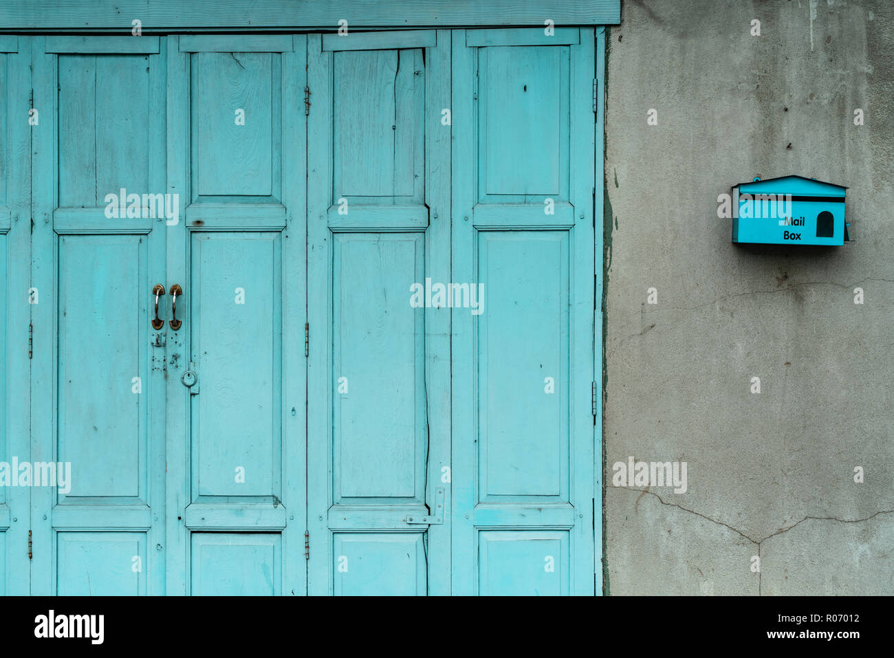 Geschlossene grüne oder blaue Tür und leeren Briefkasten auf gerissenen Beton Wand des Hauses. Altes Haus mit gecrackten Zement Wand. Vintage Haustür Abstract Stockfoto