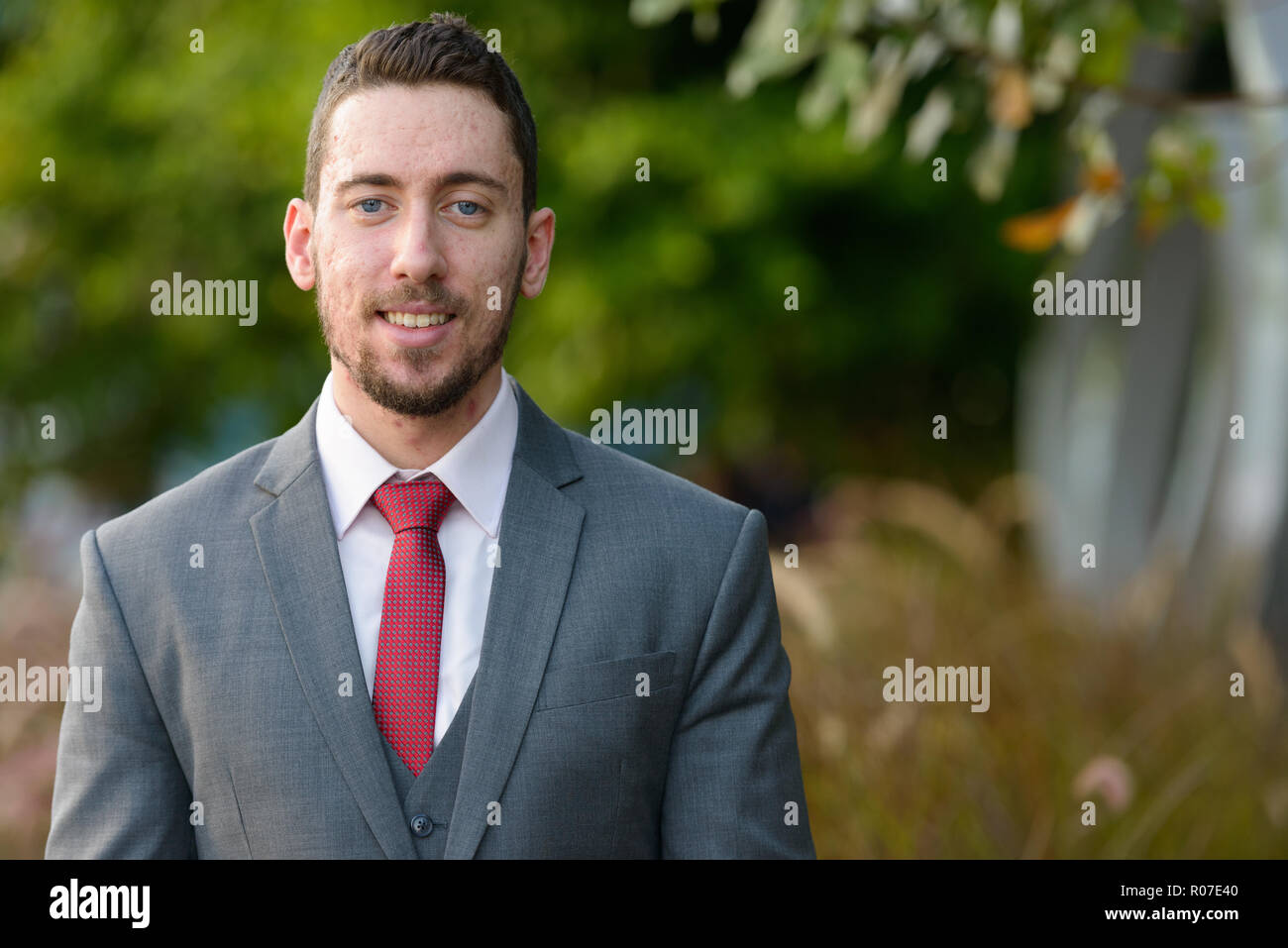 Junge Unternehmer glücklich lächelnd draußen im Park Stockfoto