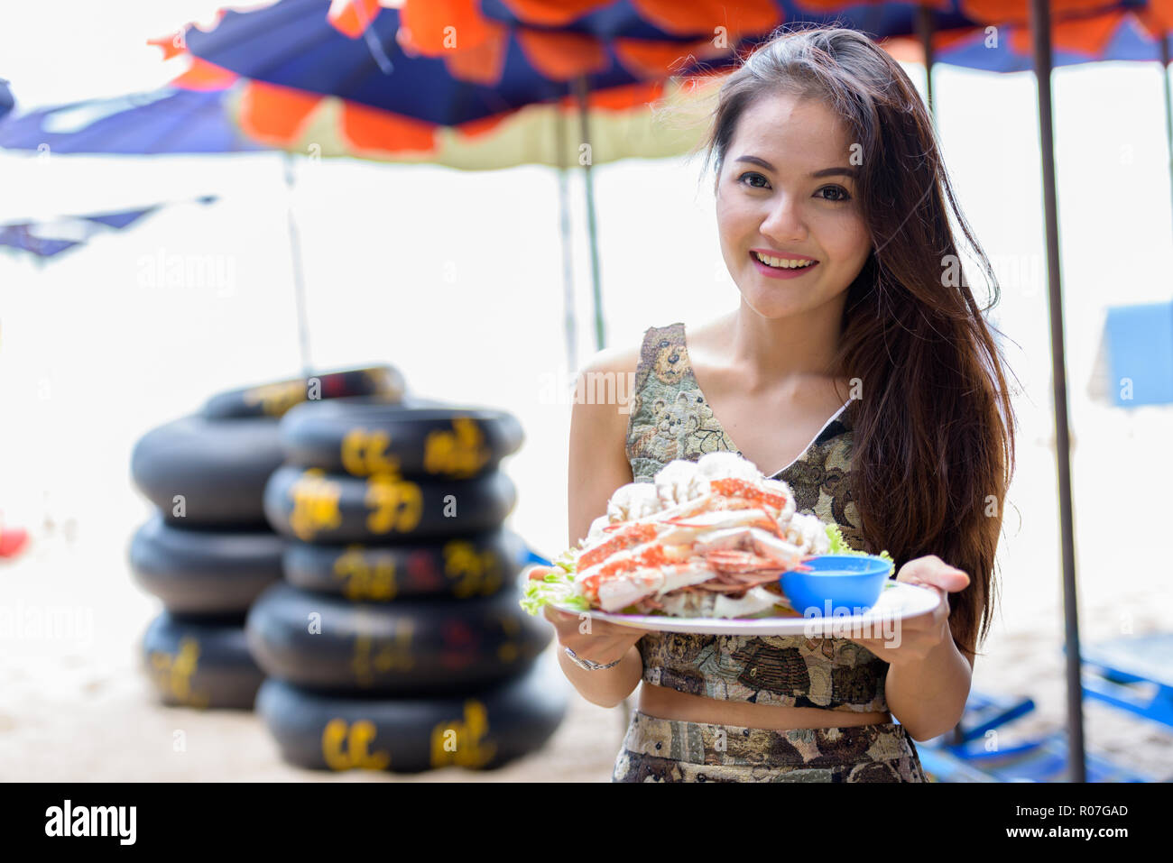 Junge glücklich schöne asiatische Frau lächelnd während Halteplatte der Stockfoto
