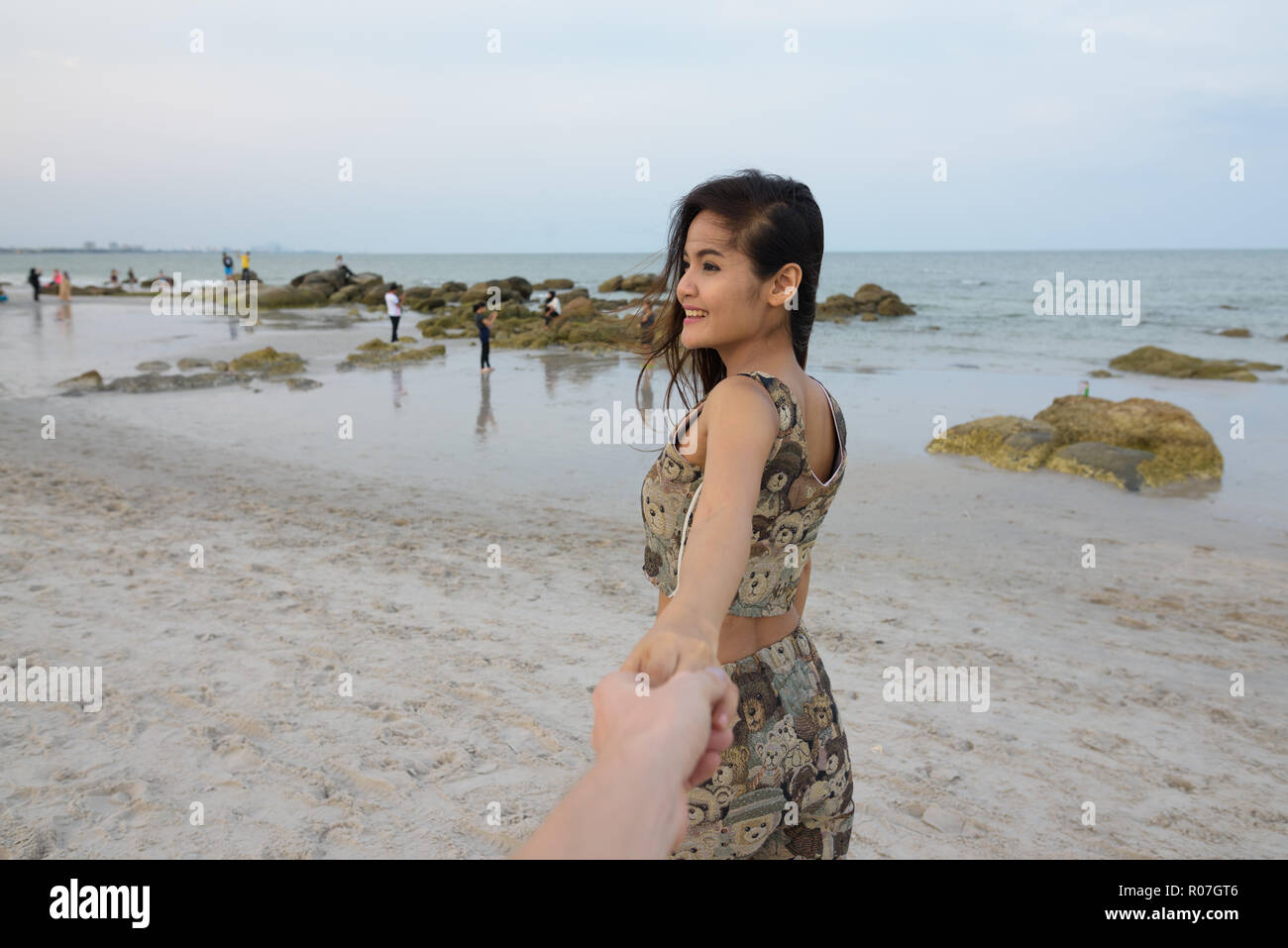 Nachdenkliche junge asiatische Frau glücklich lächelnd, während Hände halten ein Stockfoto