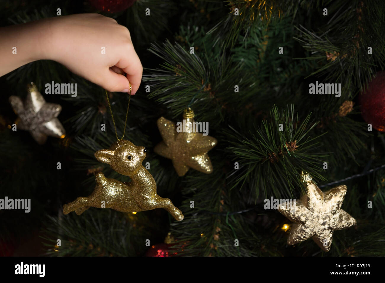 Close-up des Kindes Hand a Christmas Ornament am Baum Stockfoto