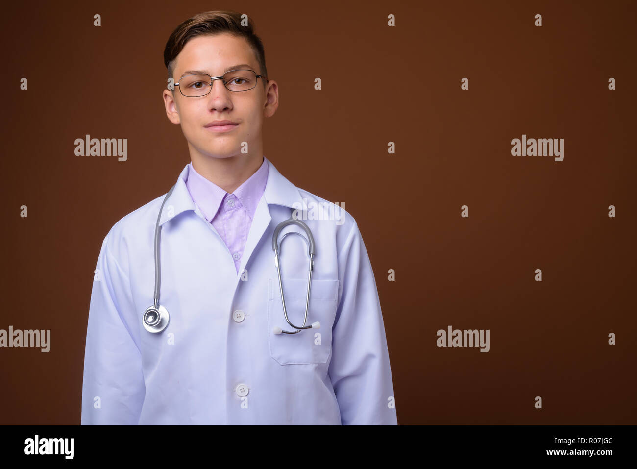 Studio shot der jungen gutaussehenden Arzt gegen braunen Hintergrund Stockfoto