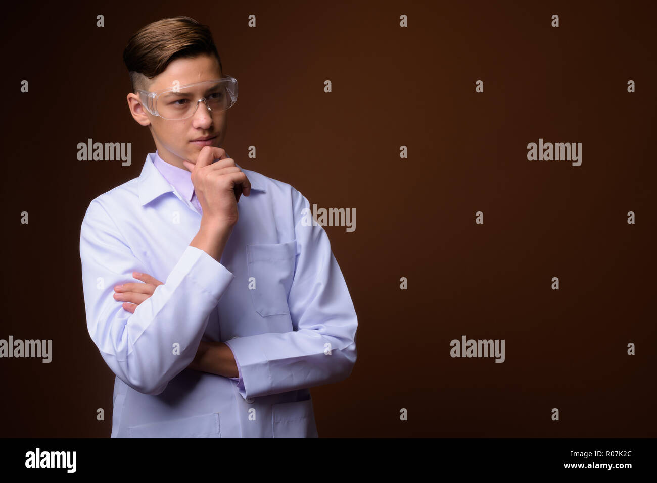 Studio shot der jungen gutaussehenden Arzt gegen braunen Hintergrund Stockfoto