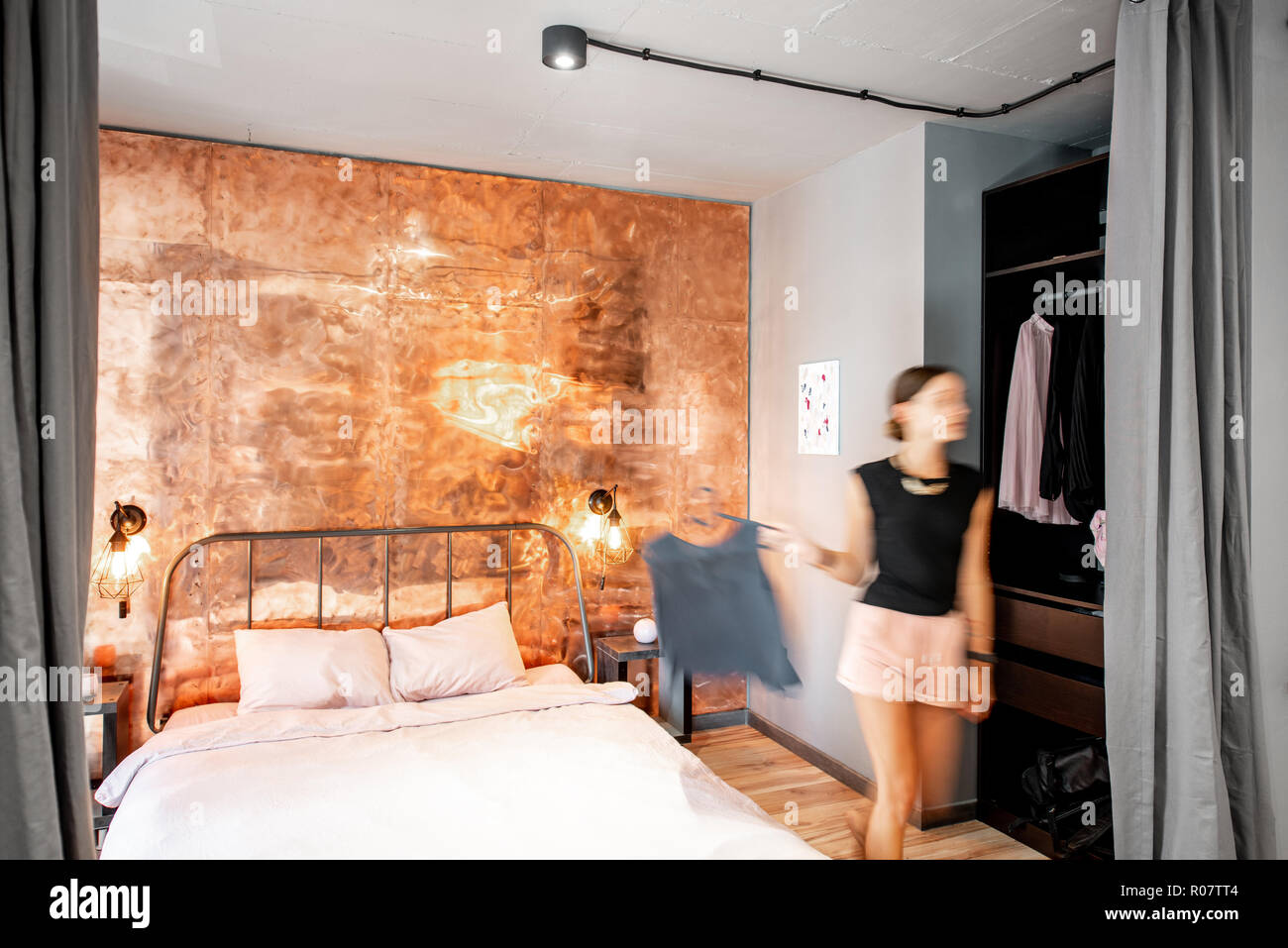 Moderne Schlafzimmer im Loft intreior mit hellem Kupfer Wand- und Bewegung  verwischt Frau gehen mit clothhes Stockfotografie - Alamy
