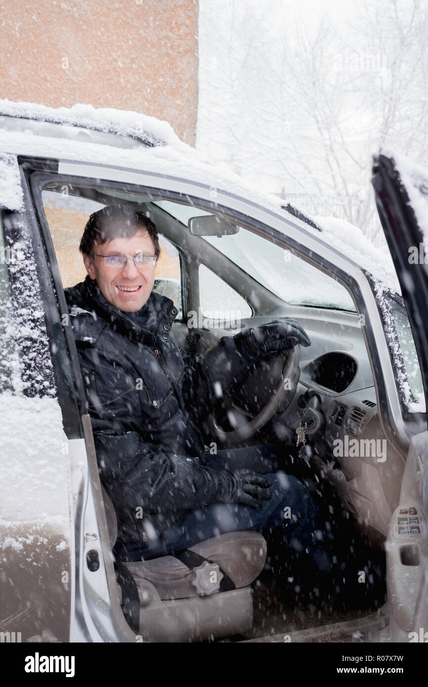 Lächelnd Mann sitzt im Auto fahren, während starker Schneefall Stockfoto