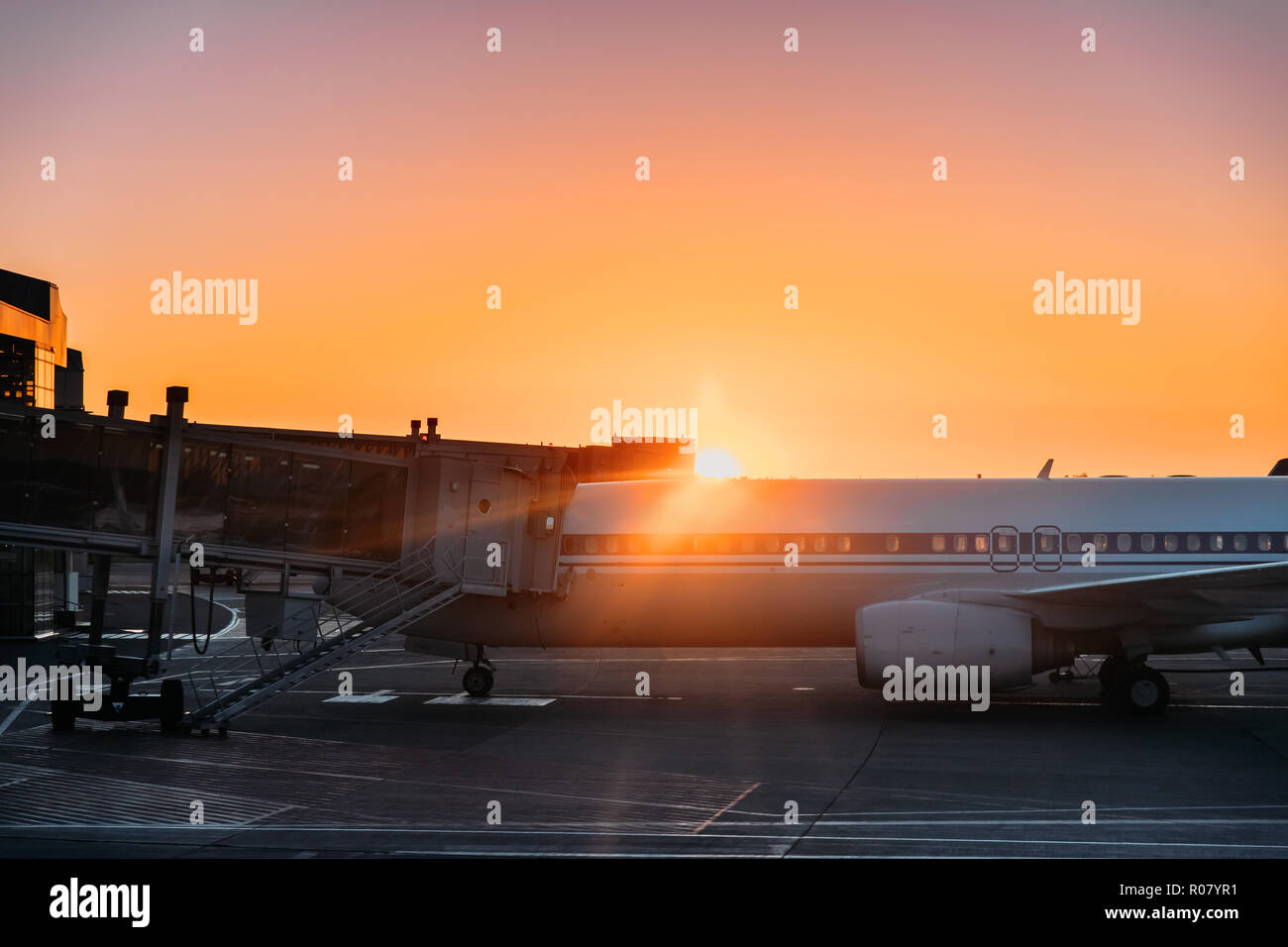 Flugzeuge Flugzeug Boarding Passagiere Flughafen im sonnigen Sonnenuntergang Sonnenaufgang. Stockfoto