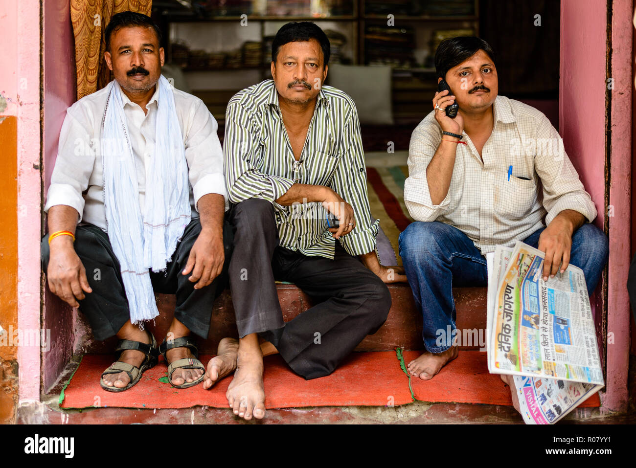 VARANASI, INDIEN - 15.August 2014: Indische Männer sitzen vor einem Geschäft (Varanasi, Indien) Stockfoto