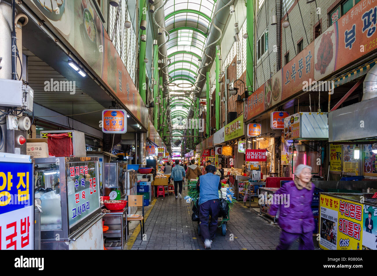 Eine Ansicht entlang einer belebten Gasse mit Ständen in der Markthalle gesäumt, Bupyeong Khangtong Markt in Busan, Südkorea. Stockfoto