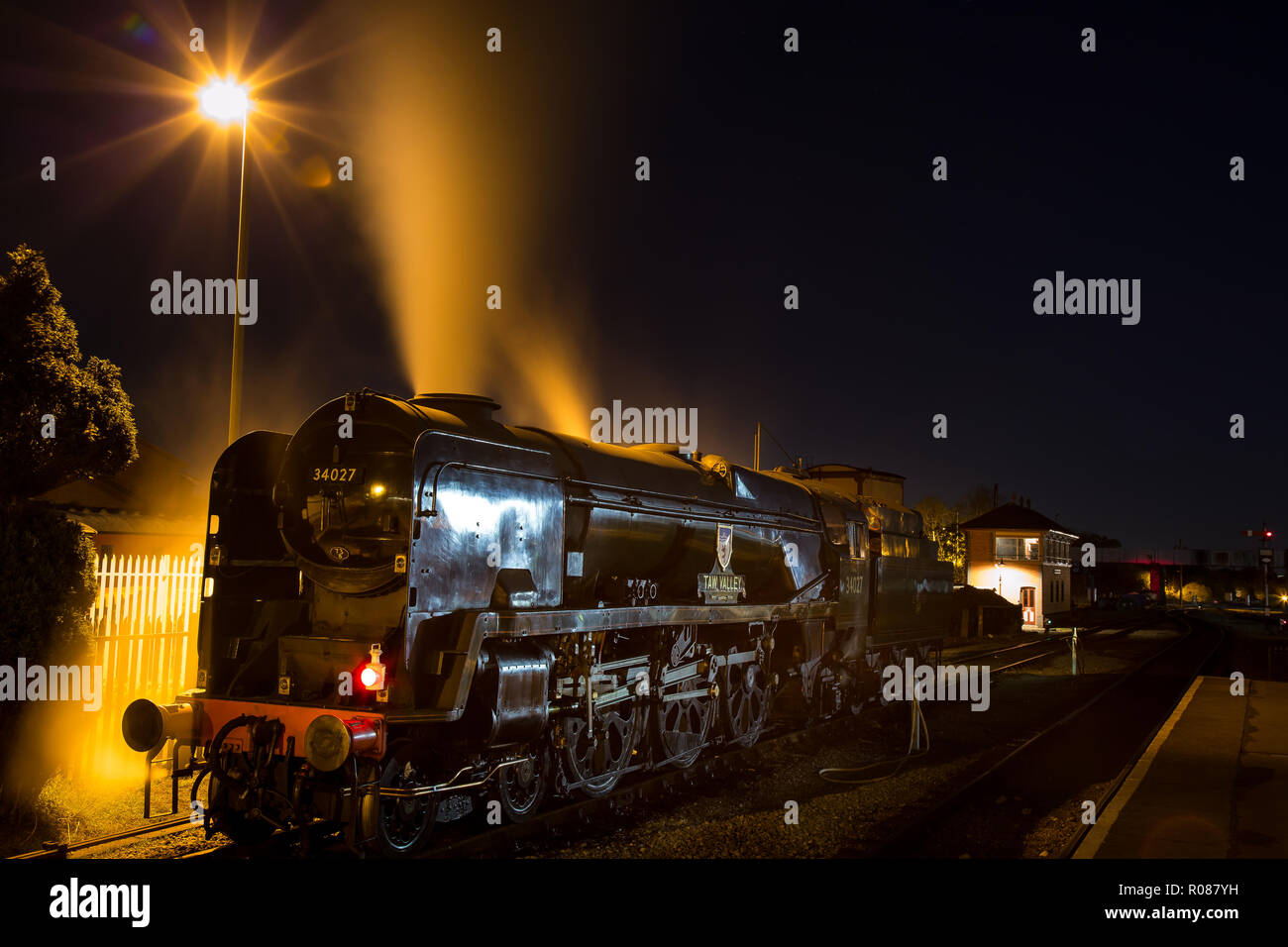 Lange Exposition, Night Shot von hinten beleuchtete, haltbar, UK Dampflokomotive, die Übernahme von Wasser bei SVR-Station in der Dunkelheit. Motor releases Dampf aus Trichter. Stockfoto