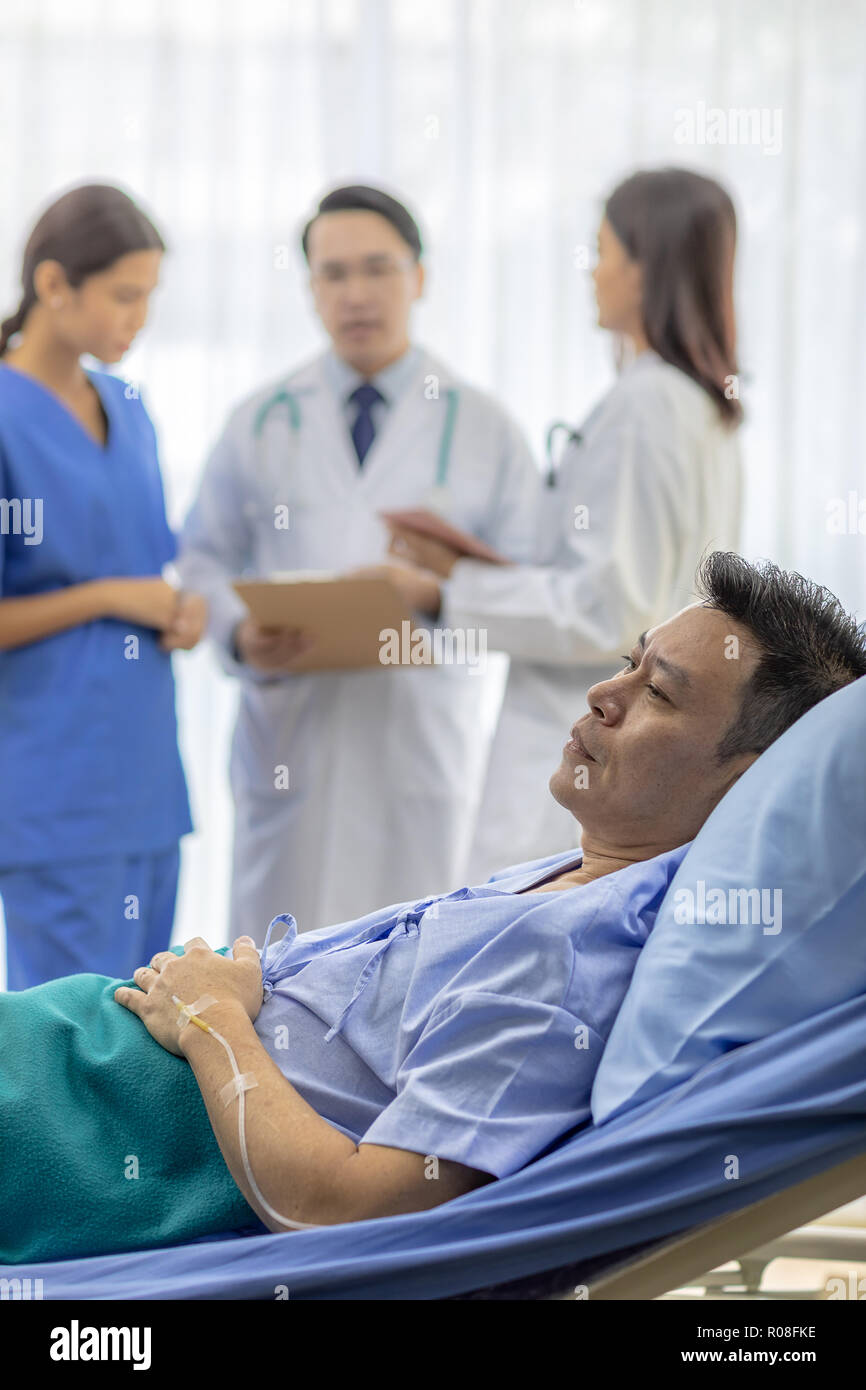 Beunruhigt Patienten in Bett mit professionellen Team Ärzte im Hintergrund Stockfoto
