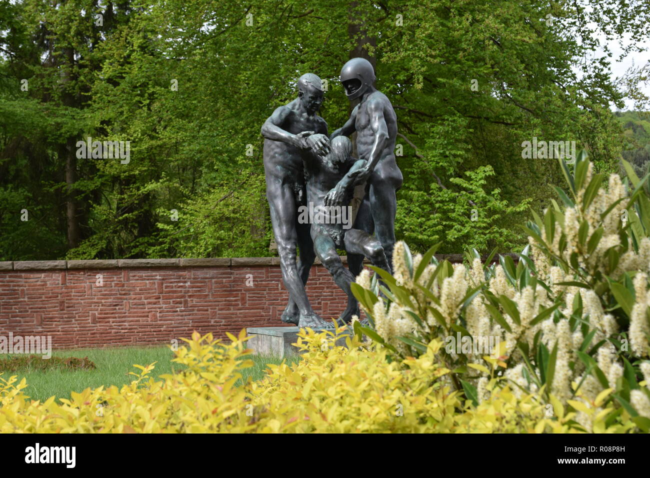 Eine Bronzestatue im Sommer im Krieg 2 Friedhof in Reimsbach zeigt zwei Männer, die ein tödliches Opfer als Symbol für die Hilflosigkeit der Menschen. Stockfoto