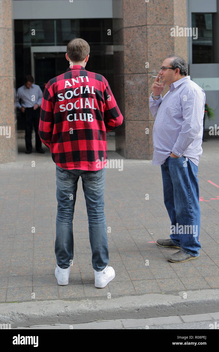 Zwei Männer rauchen einer Zigarette. Das t-shirt sagt 'Anti- Social Club'. Toronto, Ontario, Kanada. Stockfoto