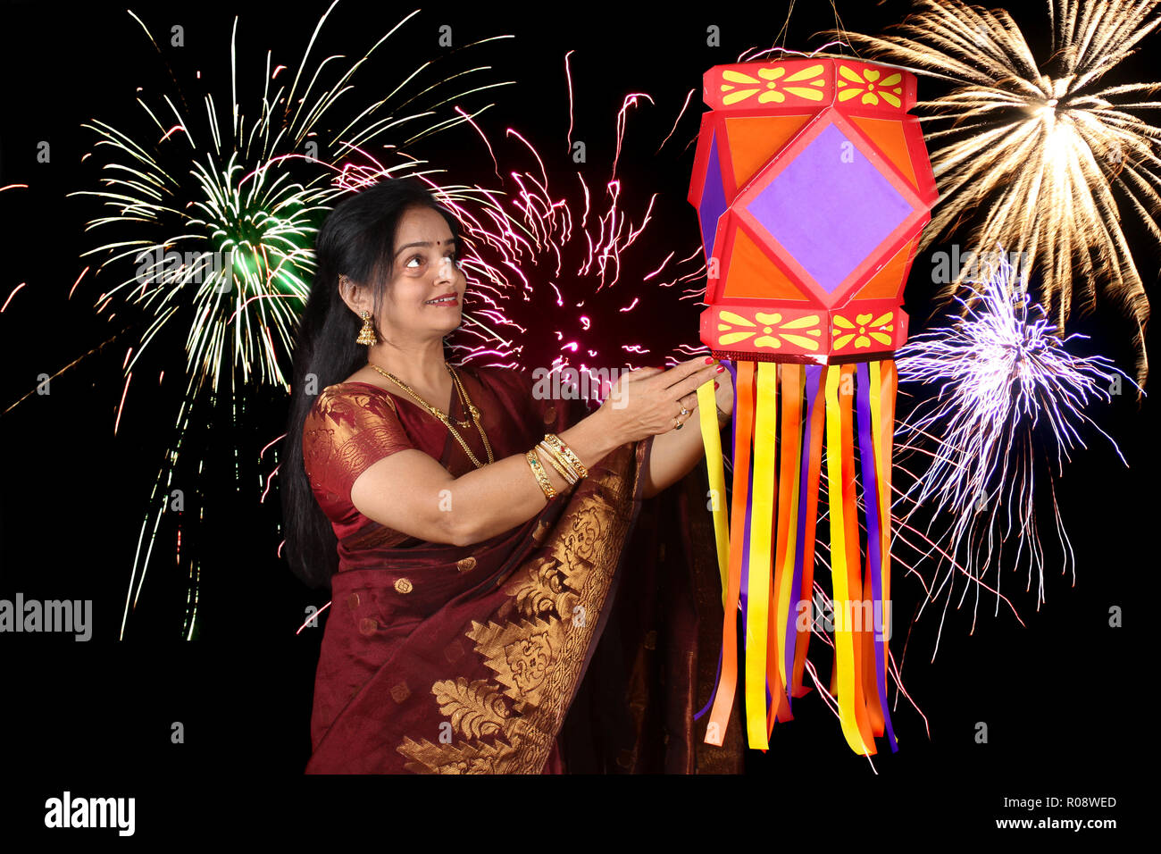 Eine indische Frau an der traditionellen Diwali Laterne während Diwali Festival in Indien suchen, vor der Kulisse von Diwali Feuerwerk. Stockfoto