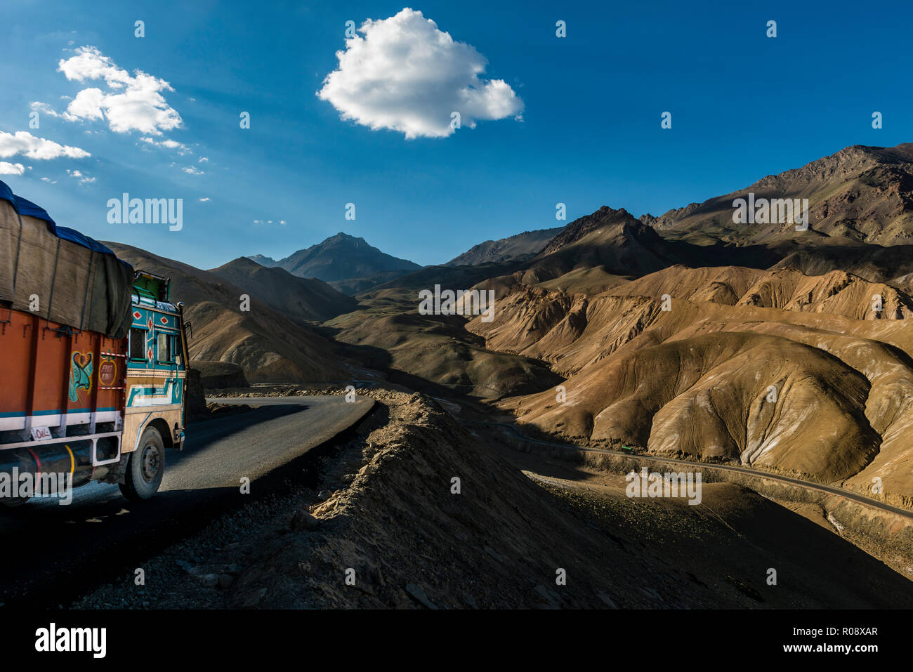 Ein Lkw fahren hinunter nach Lamayuru auf Srinagar-Leh-Highway durch eine karge Landschaft mit blauem Himmel und weißen Wolken, auf einer Höhe von 4.000 entfernt Stockfoto