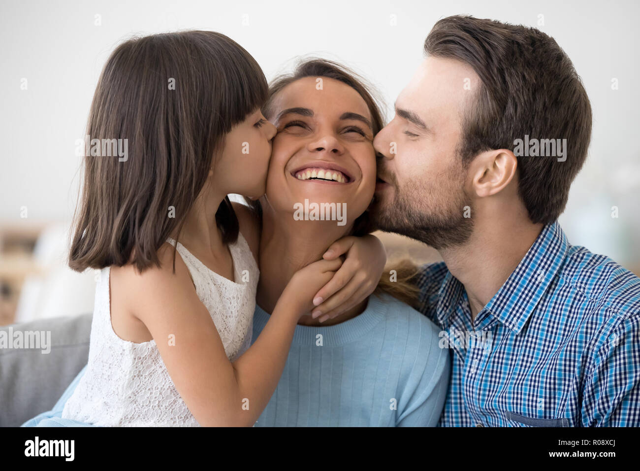 Kleines Mädchen und Mann küssen Frau Happy Family im Innenbereich Stockfoto