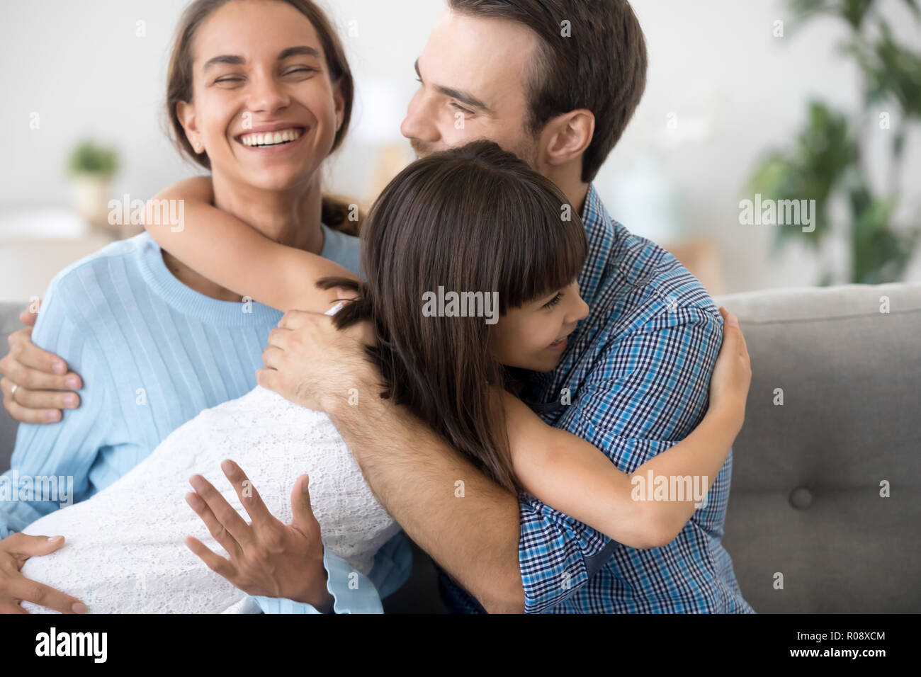 Entzückende Tochter im Vorschulalter umarmt Glücklich lächelnde Eltern Stockfoto