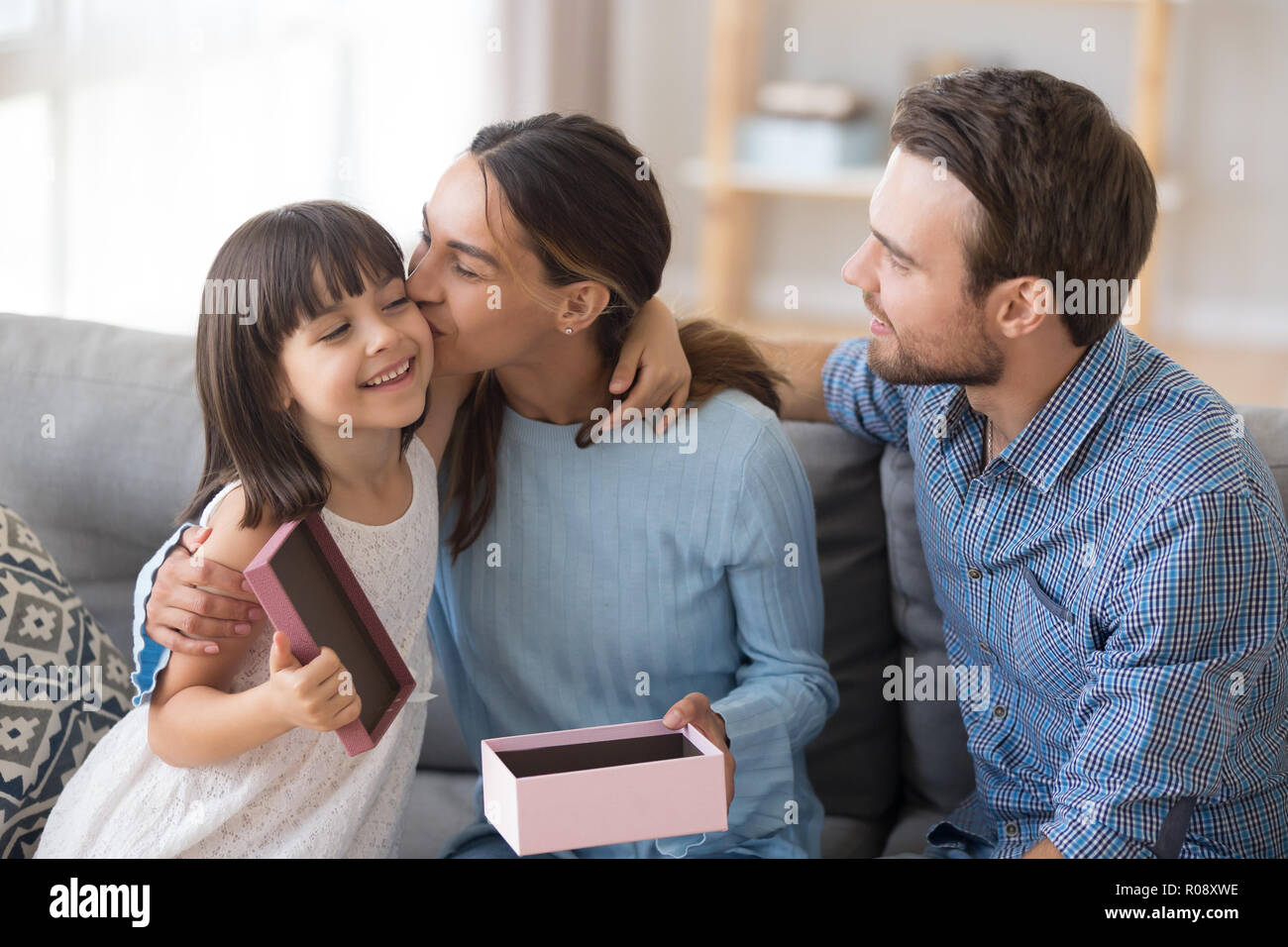 Glückliche Mutter küssen Tochter dankbar für ein Geschenk Stockfoto