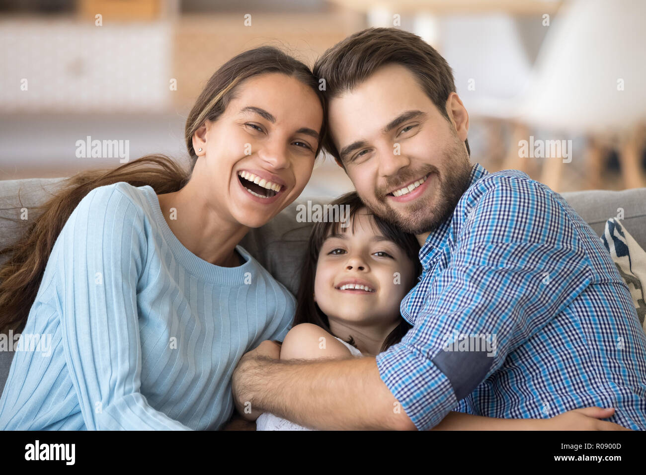 Gerne fröhliche Familie umfassende Sitzen auf der Couch zu Hause Stockfoto