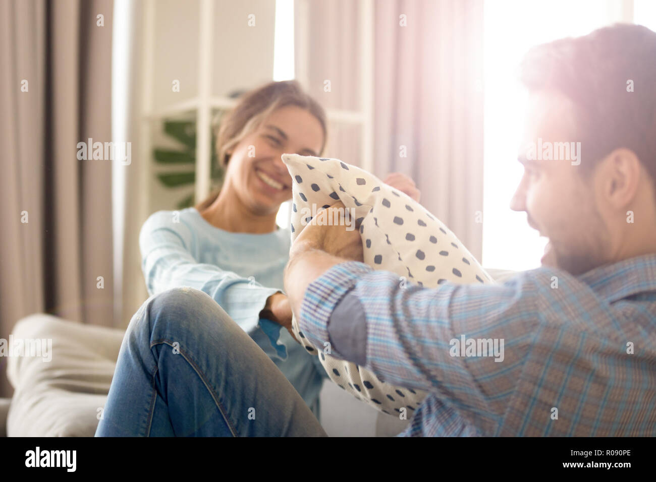 Freundliche Paar spielen kämpfen mit Kissen auf der Couch sitzen Stockfoto