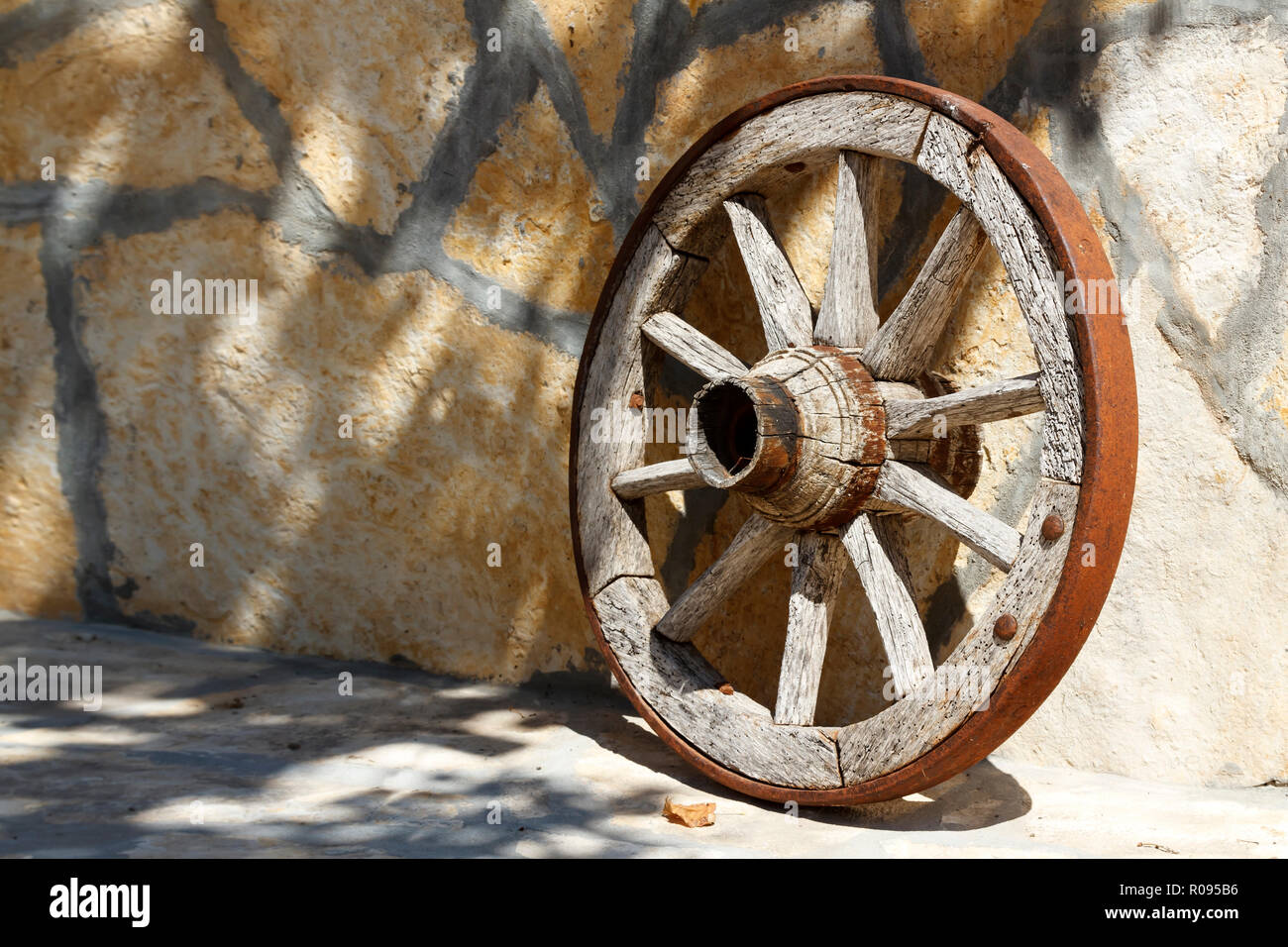 Altes, hölzernes Wagenrad gegen den Stein Wand lehnt Stockfoto