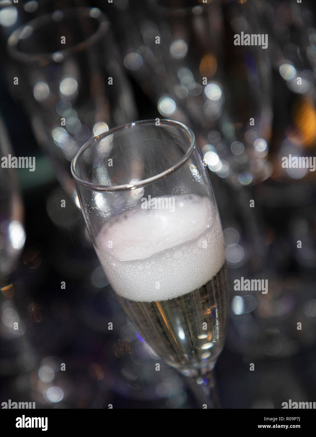 Glas Sekt nur mit einem sprudelnden Kopf gegossen. Unscharfe, bokeh Hintergrund Stockfoto