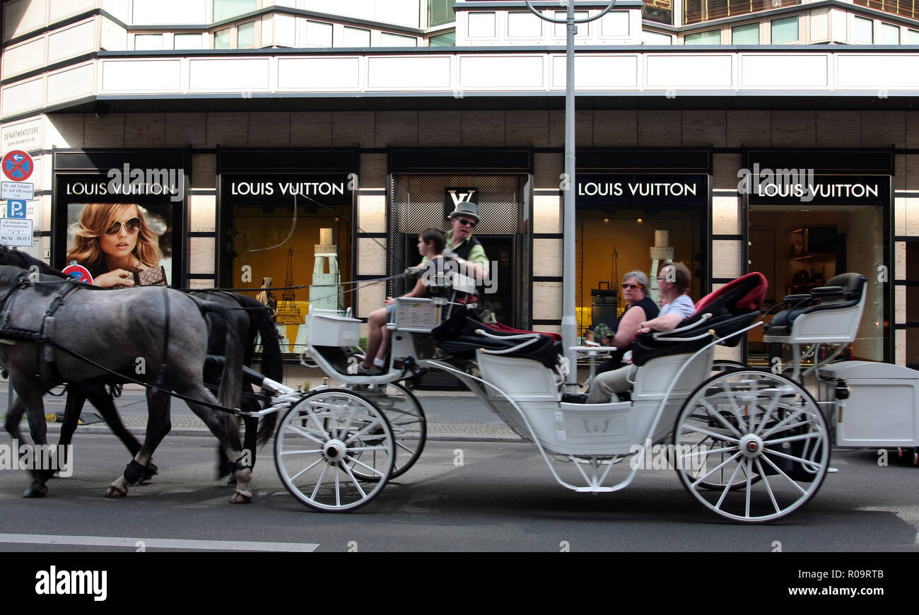 Eine riesige, Kutsche, mit seinen Passagieren, vorbei an der Louis Vuitton Kaufhaus in Berlin. Stockfoto