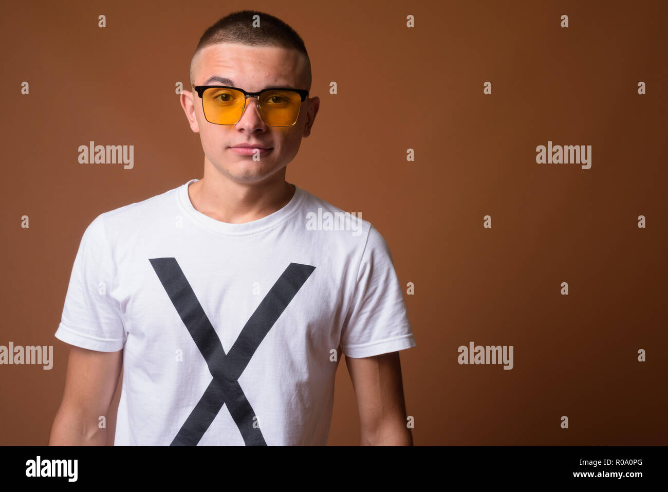 Studio shot Junger stattlicher Mann mit kurzen Haaren gegen Braun Stockfoto